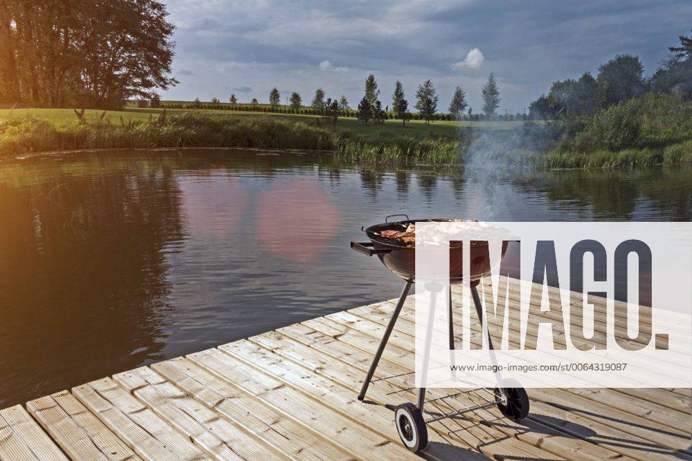 Estonia, barbecue grill on wooden platform by lake property released JAAF000194