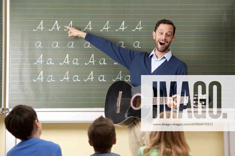 IMAGO Creative: Bildung, Musikerziehung Teacher with guitar at blackboard showing variations of letter A model released Symbolfoto property released MFRF000110