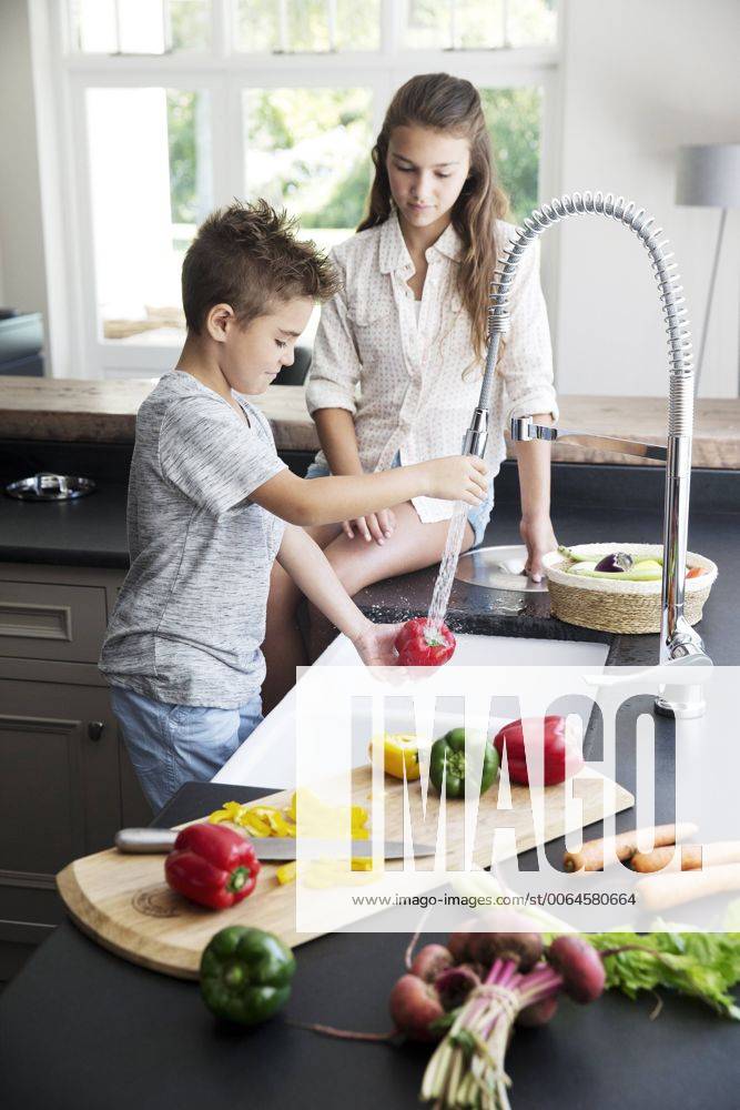 Brother and sister washing vegetables in kitchen model released Symbolfoto property released TOYF000045