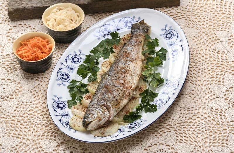 Fish plate in greek tavern. Roasted trout on onion., Pretty beige handmade table cloth.
