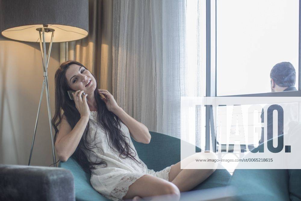 Woman telephoning in a hotel room while man waiting on the balycony model released Symbolfoto property released ZEF005430