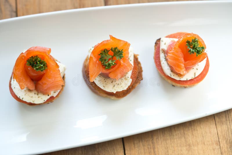 Canapes with red fish, Canapes with salmon and cheese on wooden board
