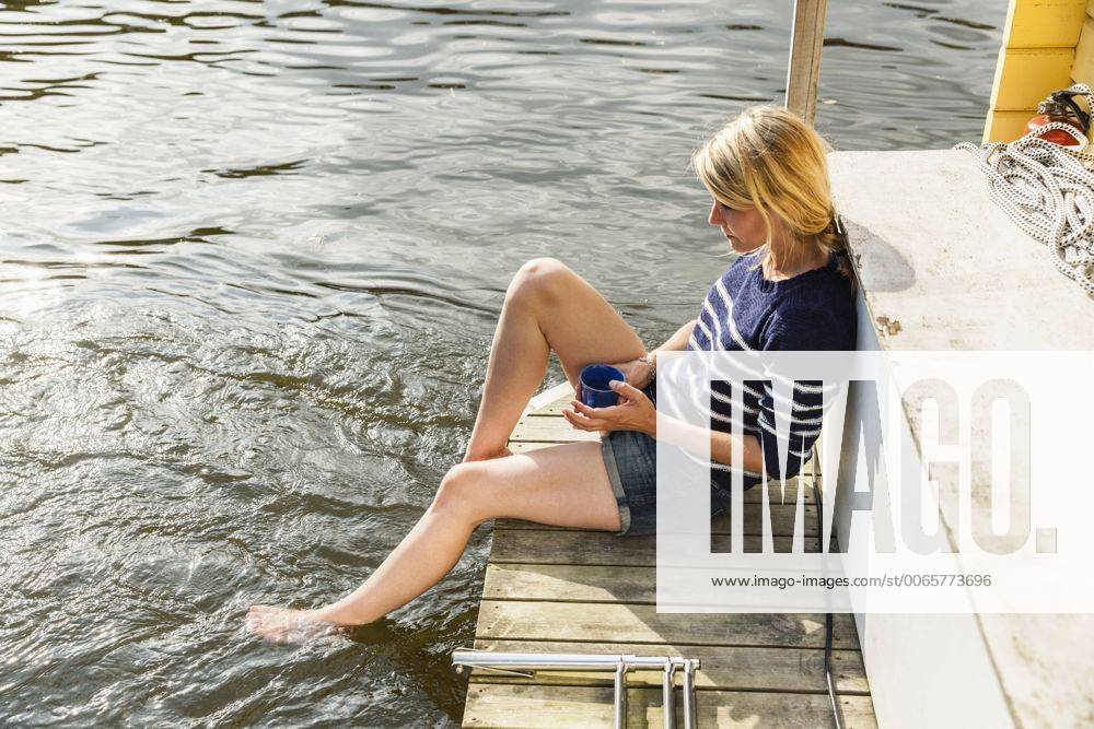 Releaxed woman on a house boat with coffee cup model released Symbolfoto property released FMKF001935