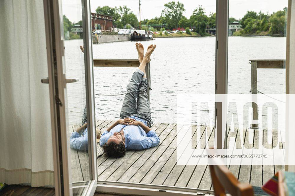 Man lying on wooden deck of a house boat model released Symbolfoto property released FMKF001973