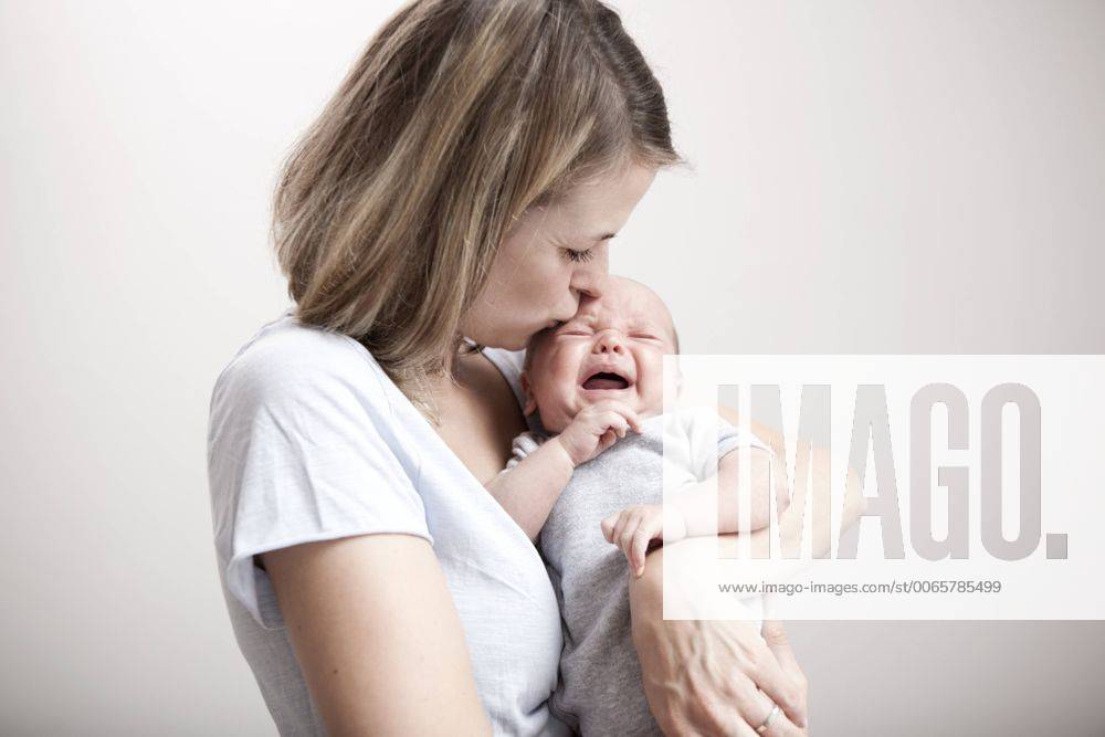 Young woman kissing crying baby model released Symbolfoto property released MFRF000295