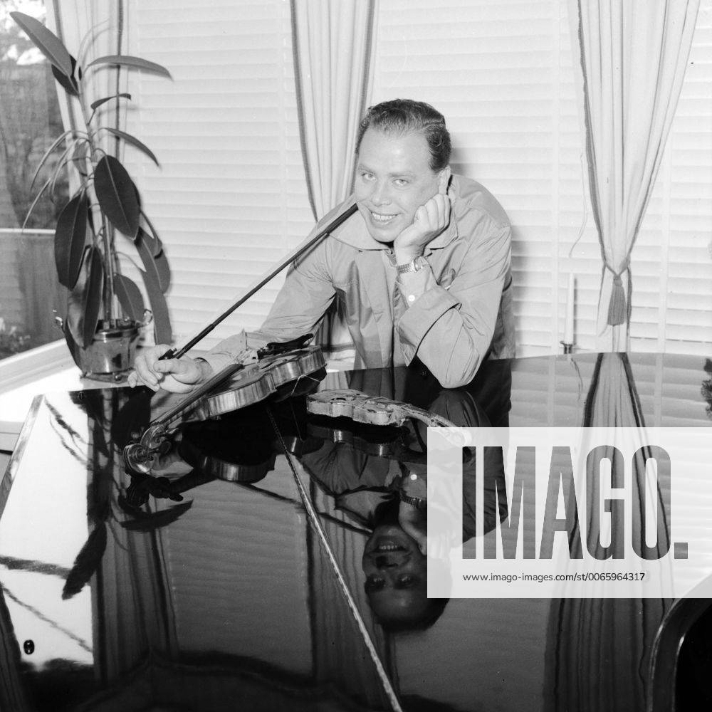 Der deutsche Violinist Helmut Zacharias und seine Geige spiegeln sich auf der polierten Oberfläche eines Flügels in Hamburg, 1955. German violinist Helmut Zacharias and his violin mirroring on the polished surface of a grnad piano in Hamburg, 1955.
