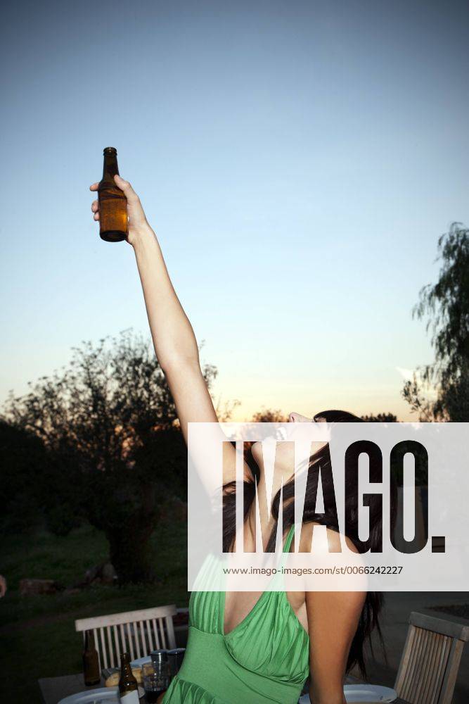 Happy young woman lifting a beer at sunset model released Symbolfoto property released TOYF001095
