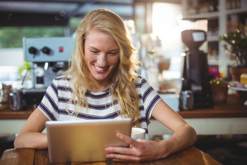 Woman sitting in a cafe using digital tablet, Smiling woman sitting in a cafe using digital tablet model released