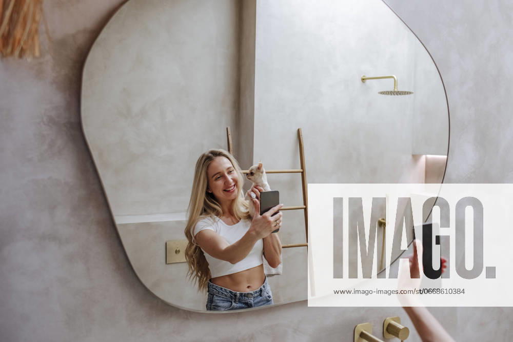 Smiling young woman taking selfie with dog in front mirror at home model released, Symbolfoto property released, MDOF02427