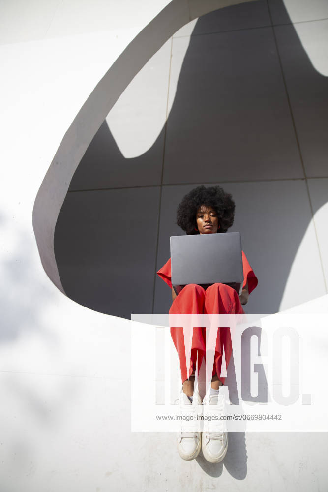 Freelancer using laptop and sitting on white wall of modern building model released, Symbolfoto, PCLF01101