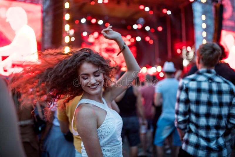 Beautiful young woman dancing at summer festival., Beautiful young women with friends dancing at summer festival.