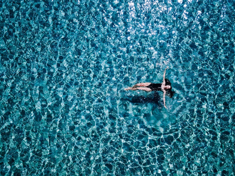 Young girl in a black swimsuit swims in the sea., Young, beautiful girl in a black swimsuit swims in the sea. model released