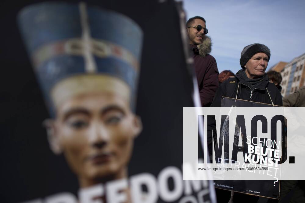 Gedenkmarsch Kolonialgeschichte DEU, Deutschland, Germany, Berlin, 27.02.2016 Demonstrant mit Plakat Freedom of Movement Schon Beutekunst betrachtet und Foto der Nofretete gegen die Kolobialgeschichte und die Aneigung afrikanischer Kulturgueter durch deutsche Museen und dem Humboldt Forum beim 10. Gedenkmarsch zur Erinnerung an die afrikanischen Opfer von Versklavung, Kolonialismus und rassistischer Gewalt vom Komitee fuer ein afrikanisches Denkmal in Berlin und afrikanischer Vereine in Berlin. Dieser Gedenkmarsch wurde ins Leben gerufen, um der Forderung nach Anerkennung der Verbrechen gegen Schwarze Menschen und Menschen afrikanischer Herkunft Nachdruck zu verleihen. Anlass ist die Berliner Afrika-Konferenz von 1884 - 1885, auf der Afrika vor 130 Jahren unter den europaeischen Kolonialmaechten aufgeteilt wurde. Mehr als 30 Millionen Afrikanerinnen und Afrikaner wurden Opfer von Verskla
