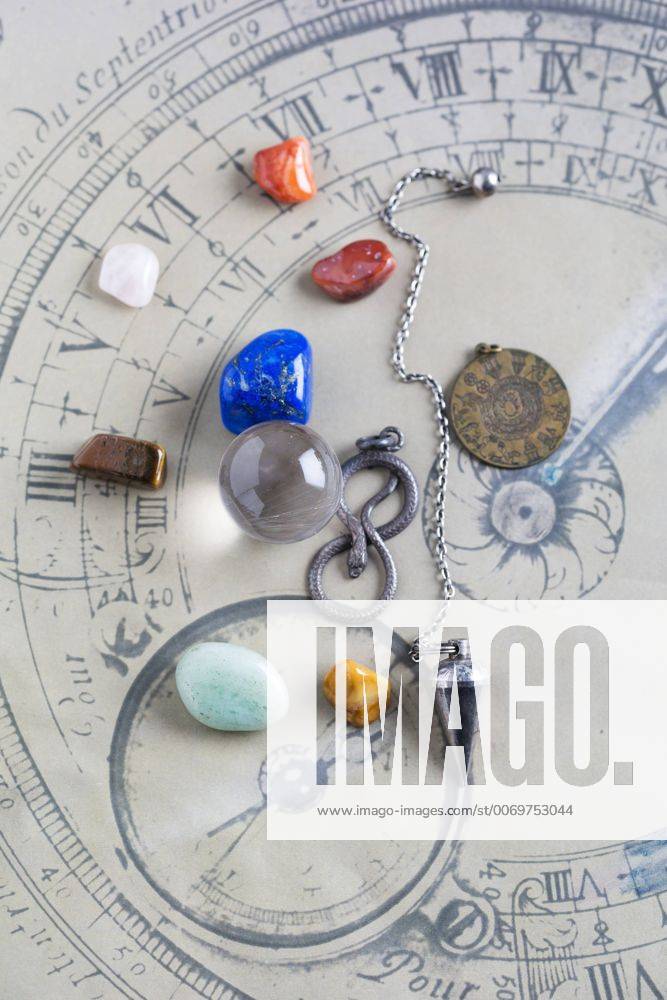 IMAGO Creative, Lifestyle, Esoterik gefährlicher Glaube Semiprecious stones, pendulum, pendant and crystal ball on horoscope circle MYF001325