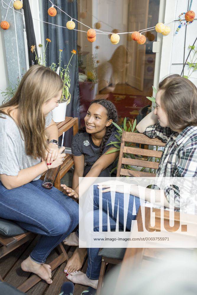 IMAGO Creative, Lifestyle, Leben in einer Wohngemeinschaft, WG Three teenage girls sitting on a balcony talking and smiling model released Symbolfoto property released OJF000103