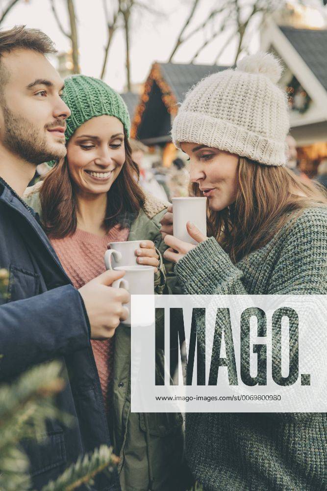 IMAGO Creative: Kimawandel - Weihnachten, Weihnachtsessen vegan Three friends having a hot punch on the Christmas Market model released Symbolfoto MFF002674