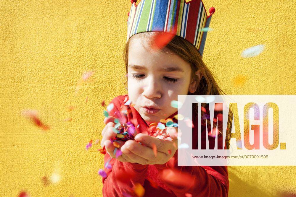 Portrait of little girl wearing paper crown blowing confetti model released Symbolfoto VABF000211