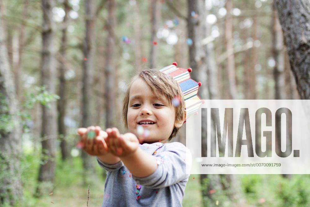 Portrait of smiling little boy wearing paper crown catching confetti model released Symbolfoto VABF000335