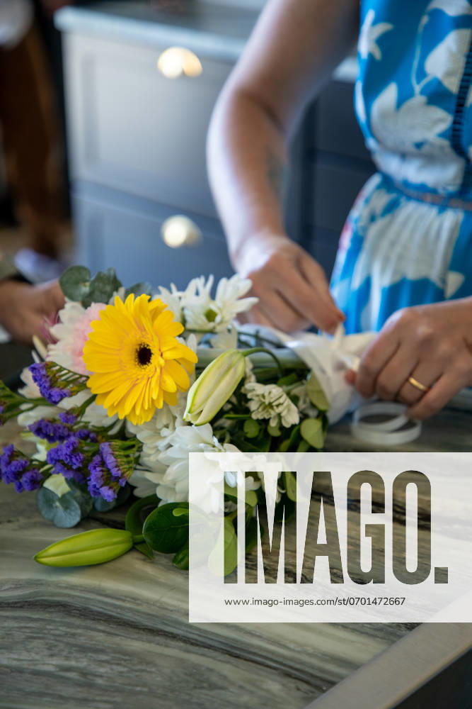 Person arranging a bouquet of colorful flowers on a marble table United States, Washington, Cheney R_XICN240618-1453372-01