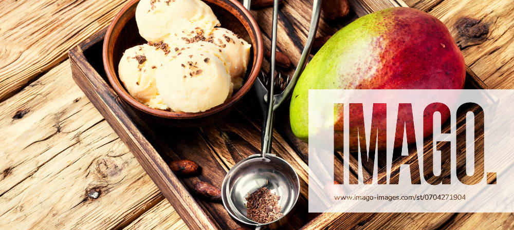 Ice cream with mango flavor. Ice cream, mango fruit and a spoon for ice cream in wooden tray ,model released, Symbolfoto