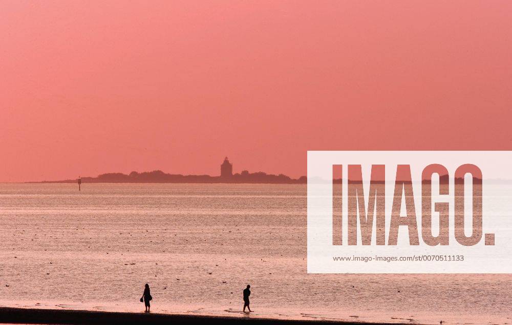 Paar bei Flut im Watt vor der Hamburger Insel Neuwerk im Abendlicht, Deutschland, Hamburgisches Wattenmeer-Nationalpark two person in the wadden sea in front of the Wadden Sea in the evening, Germany, Hamburgisches Wattenmeer National Park BLWS422757