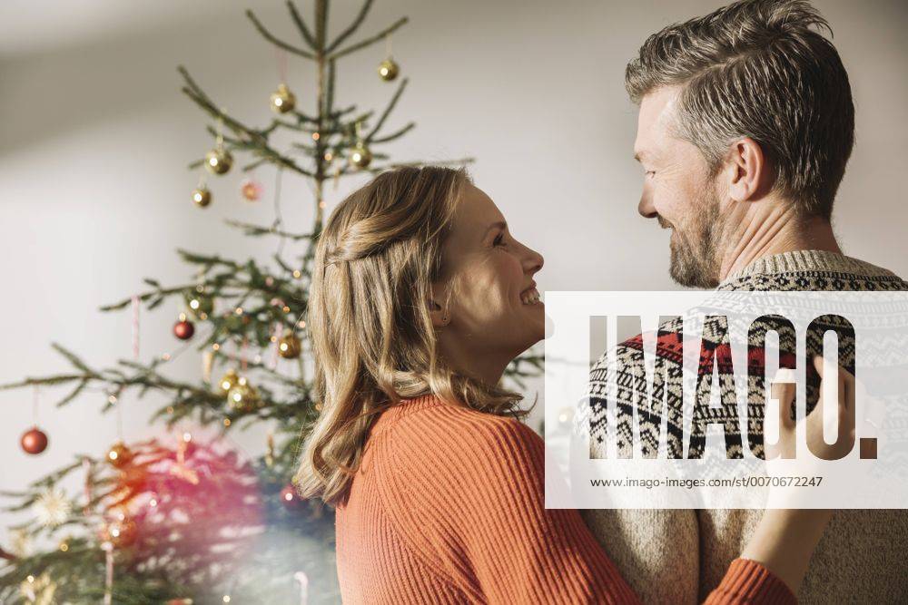 Happy couple standing in front of Christmas tree model released Symbolfoto property released MFF002817
