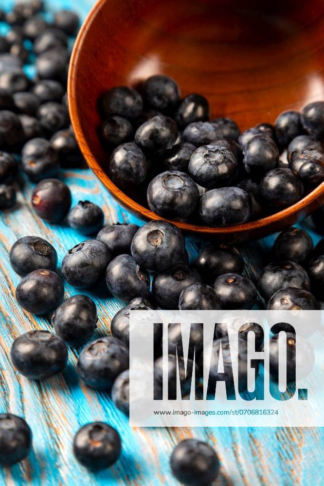 Scattered blueberries from a wooden bowl on a blue background ,model released, Symbolfoto