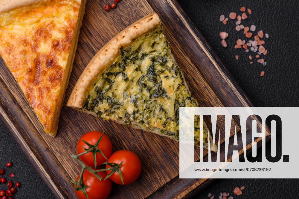 Delicious crispy quiche cut into slices with cheese, broccoli, tomatoes Delicious crispy quiche cut into slices with cheese, broccoli, tomatoes, salt, spices and herbs on a dark concrete background