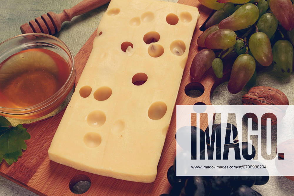 Cheese With Big holes, emmental, maasdam, Brie cheese, ON a Cutting board, With grapes and honey, nuts, appetizer to wine, Top View
