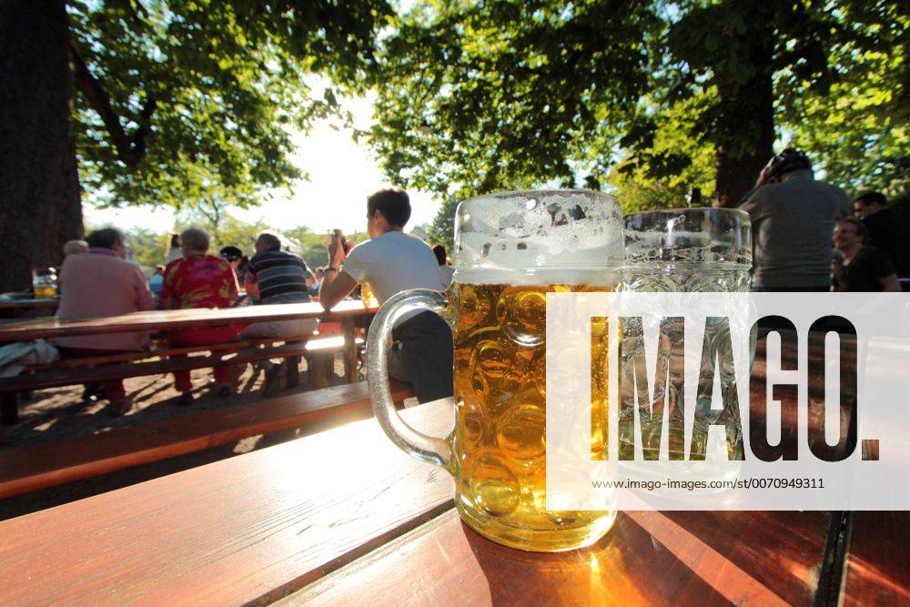 Geleerte sowie halb gefüllte Maß Bier stehen am Muttertag auf einem Biertisch in der Abendsonne im Biergarten Königlicher Hirschgarten in München, Bayenr, Deutschland