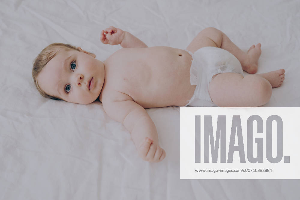Innocent baby boy in diaper lying on bed at home model released, Symbolfoto, AAZF01945