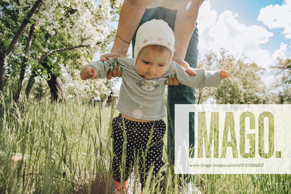 Baby girl walking with help of mother in garden model released, Symbolfoto, ADF00382