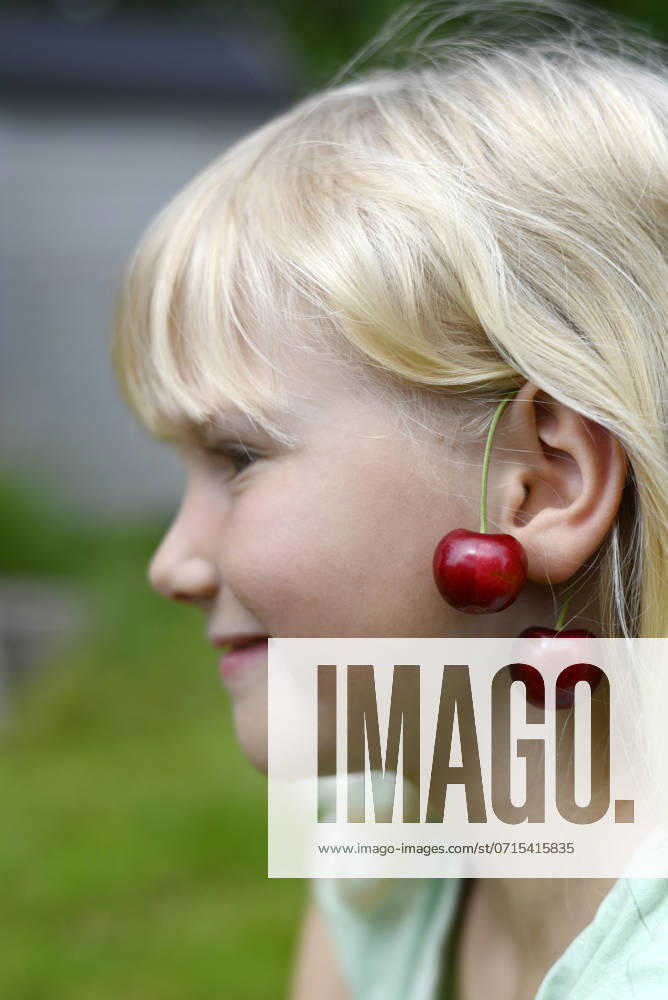 IMAGO Creative, Jahreszeit Sommer, Kirschen Smiling blond girl with cheeries hanging on ear model released, Symbolfoto, Hamburg Hamburg Deutschland Altes Land GISF01103