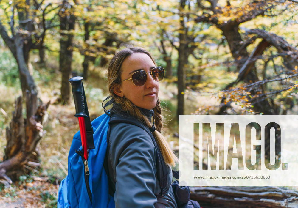 A woman wearing sunglasses on a log in a forest El Chaltén, Santa Cruz Province, Argentina CR_YBTM240722-1494054-01 ,model released, Symbolfoto