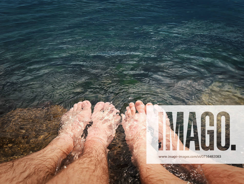 Close up of two male legs in the clear sea water. Summer vacation, resting and relaxation concept ,model released, Symbolfoto