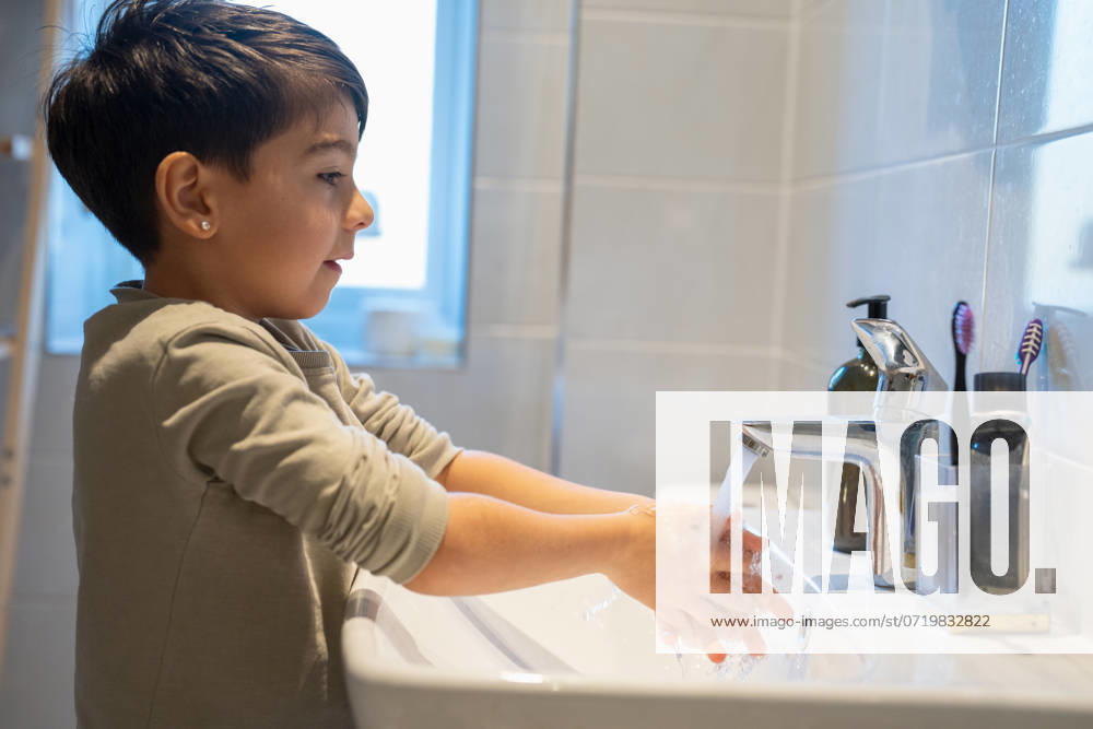 Boy (6-7) washing hands in bathroom model released