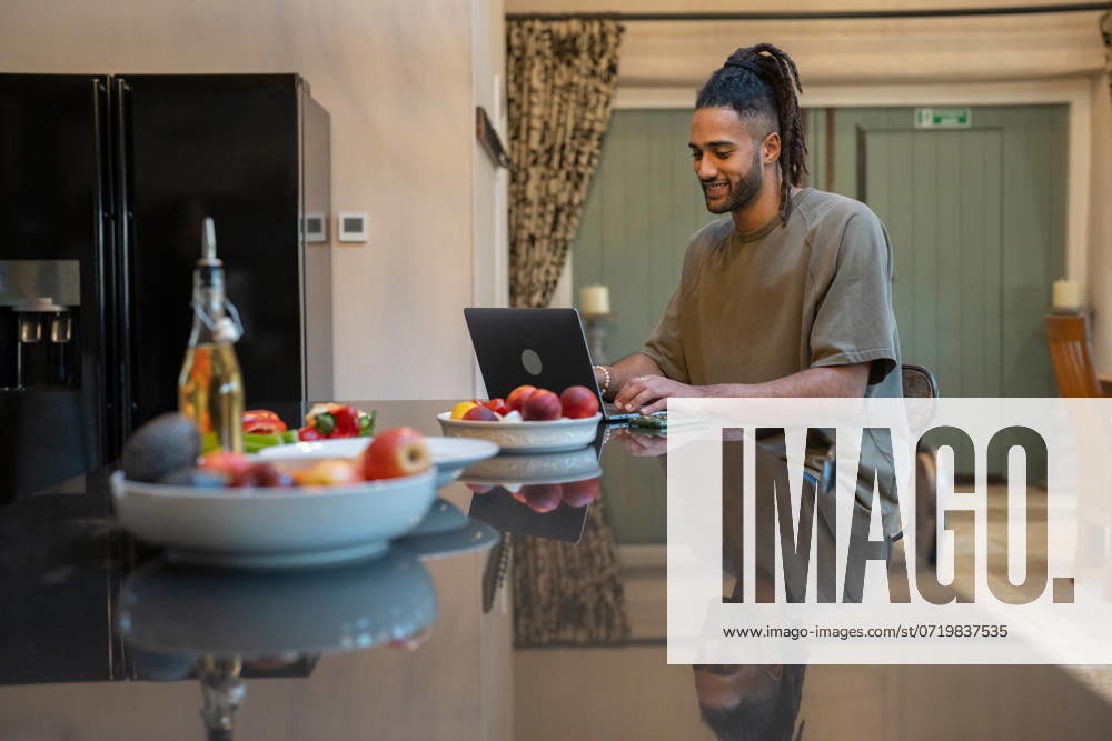 Man with dreads working on laptop at home model released