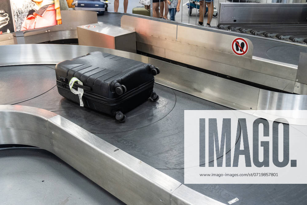 A black suitcase moves along a baggage carousel at the airport. Symbolic image Arrival after a flight and the waiting time for luggage