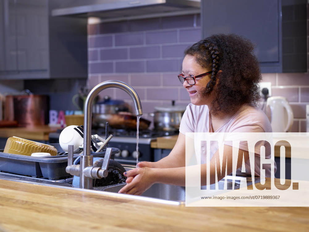 Girl with Down syndrome washing hands in kitchen sink model released