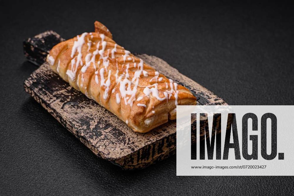 Delicious crispy braided bun with raisins inside and white icing, Delicious crispy braided bun with raisins inside and white icing outside on a dark concrete background, Delicious crispy braided bun with raisins inside and white icing outside on a dark concrete background, 28.09.2023,