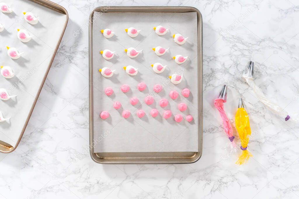 Piping meringue with piping bags into the baking sheet lined with parchment paper to bake Easter meringue cookies.