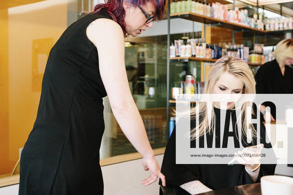 A hair stylist and a client, a young woman with long blonde hair, at a hair salon. A hair stylist and a client, a young woman with long blonde hair, at a hair salon. 21692
