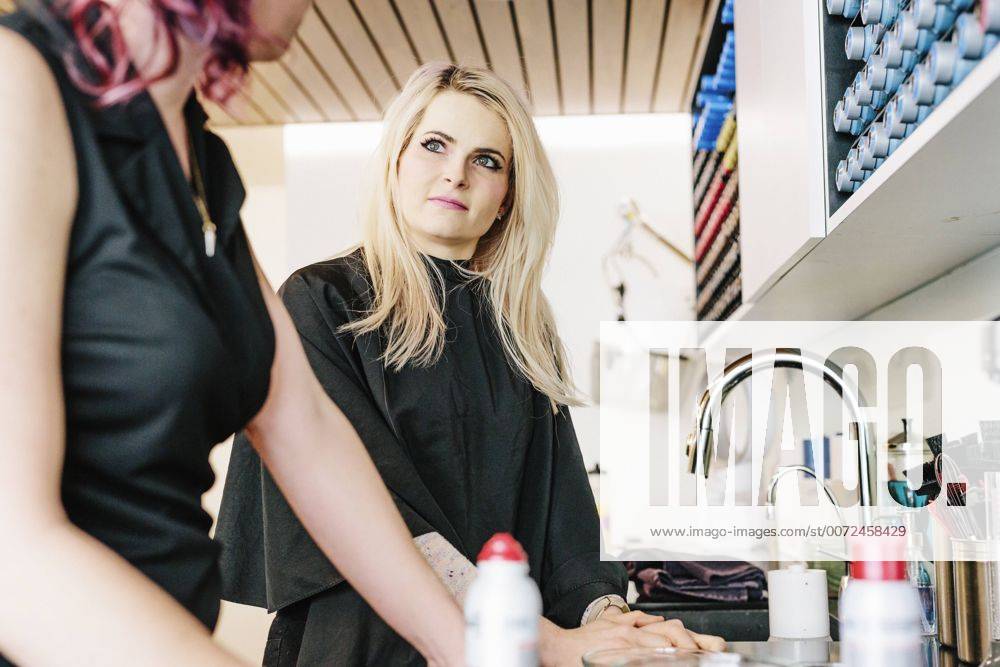A hair stylist and a client, a young woman with long blonde hair, at a hair salon. A hair stylist and a client, a young woman with long blonde hair, at a hair salon. 21693