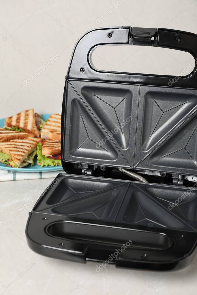 Modern grill maker and sandwiches on white table