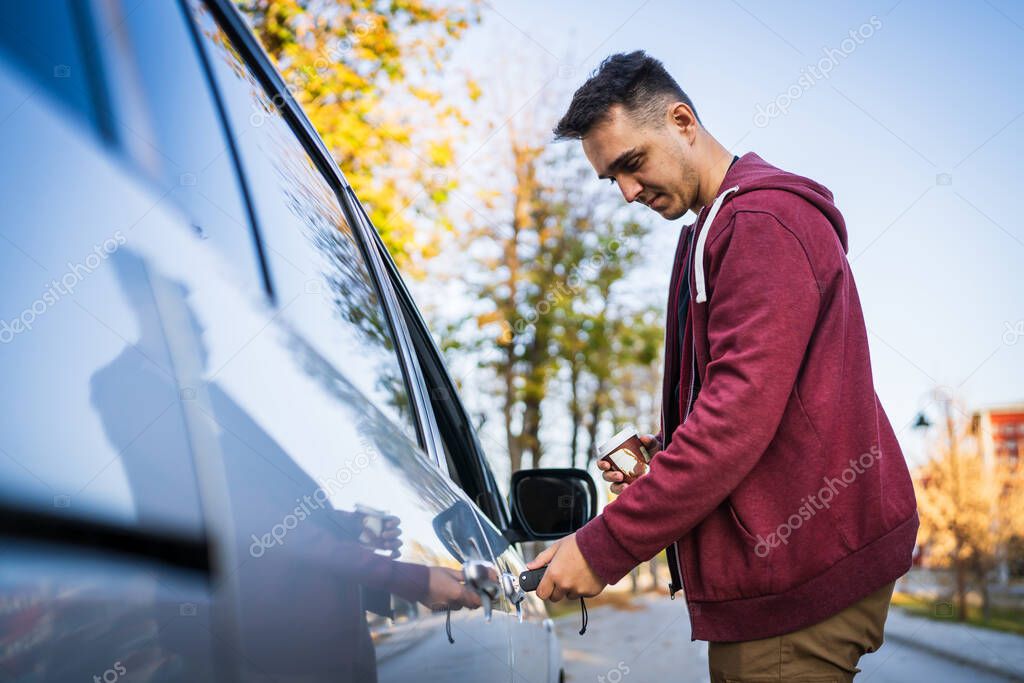 Side view caucasian man holding car keys locking or unlocking the vehicle door