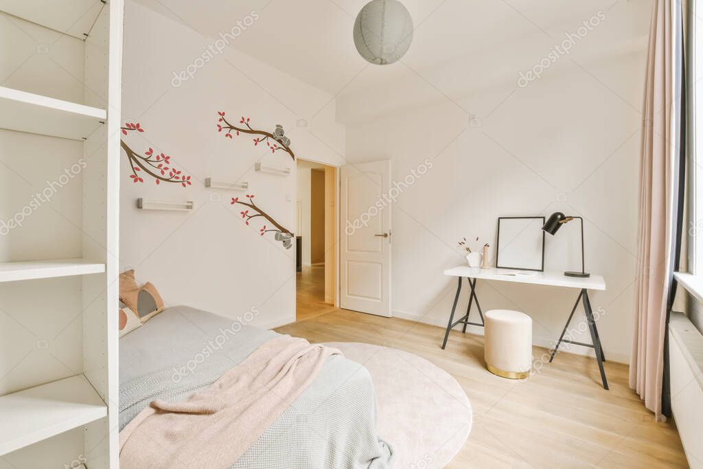 A bedroom with a bed, desk and book shelf in the room is white and has pink flowers on it