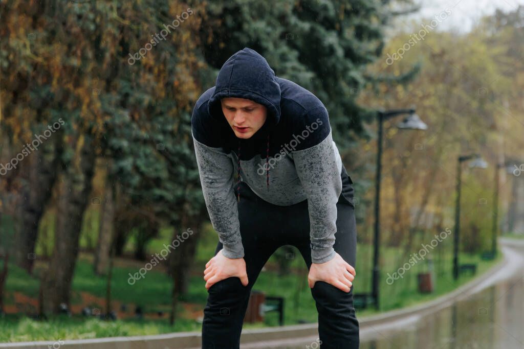 Training in the Elements A Guys Outdoor Fitness Regimen on a Rainy Day. A young man training in the rain, his focus and commitment to fitness evident in his intense workout session.