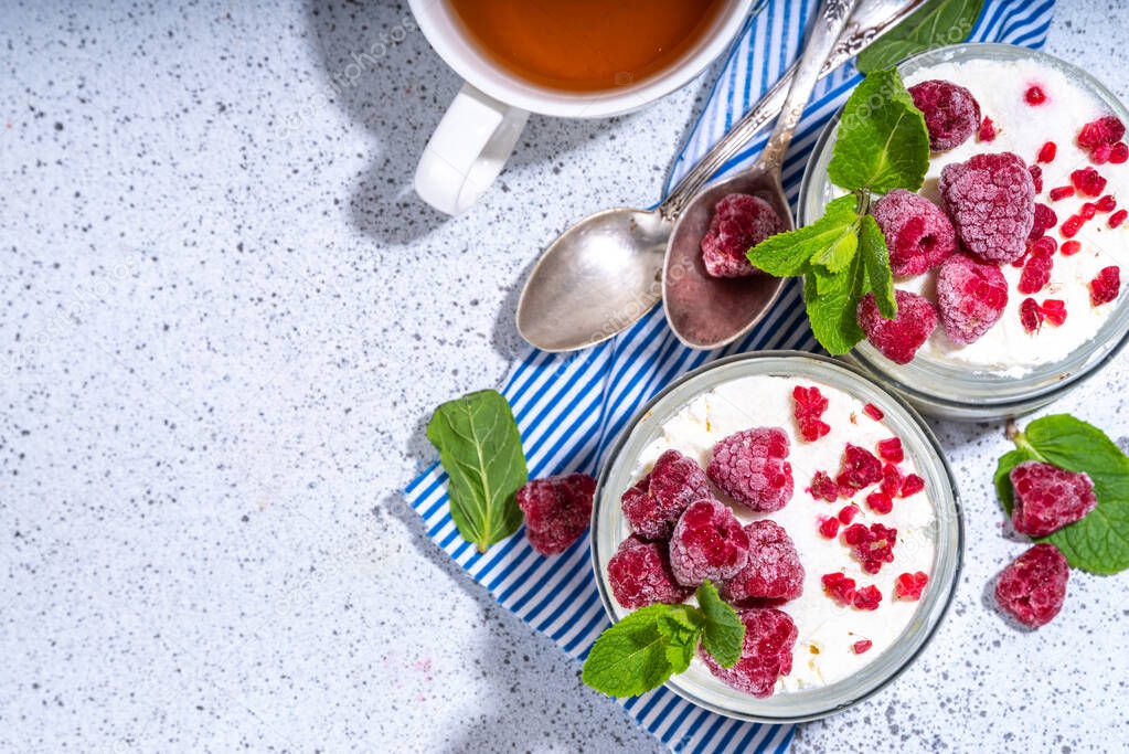 IMAGO Creative, Food, High Protein Frühstück Overnight cheesecake oatmeal. Cheesecake morning breakfast layered parfafait dessert with homemade cottage cheese, mascarpone, oats and fresh raspberries, on sunny white concrete background copy space