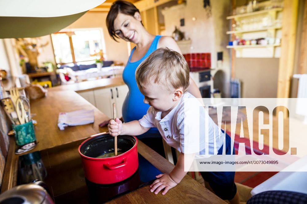 Little boy helping his pregnant mother to cook, stirring in pot model released Symbolfoto property released HAPF000603