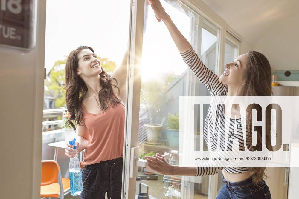 IMAGO Creative, Lifestyle, Leben in einer Wohngemeinschaft, WG Youniverse - Urban Lifestyle Two women cleaning window together model released Symbolfoto property released PESF000332